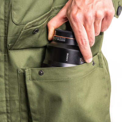 Photographer using one of the pockets on the field jacket to store a lens 