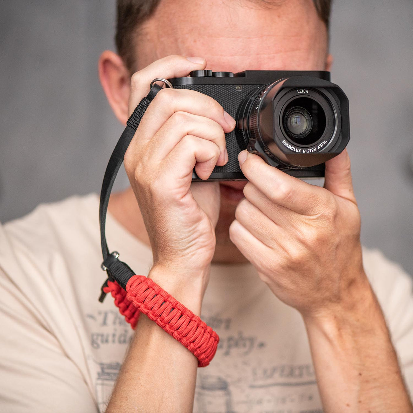 Photographer using Leica camera with Leica Paracord hand strap 