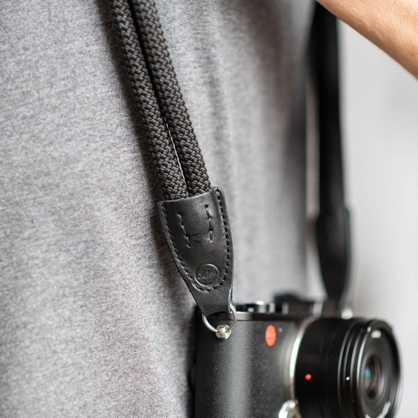 Leica camera on a photographer's hip held with black double rope strap 