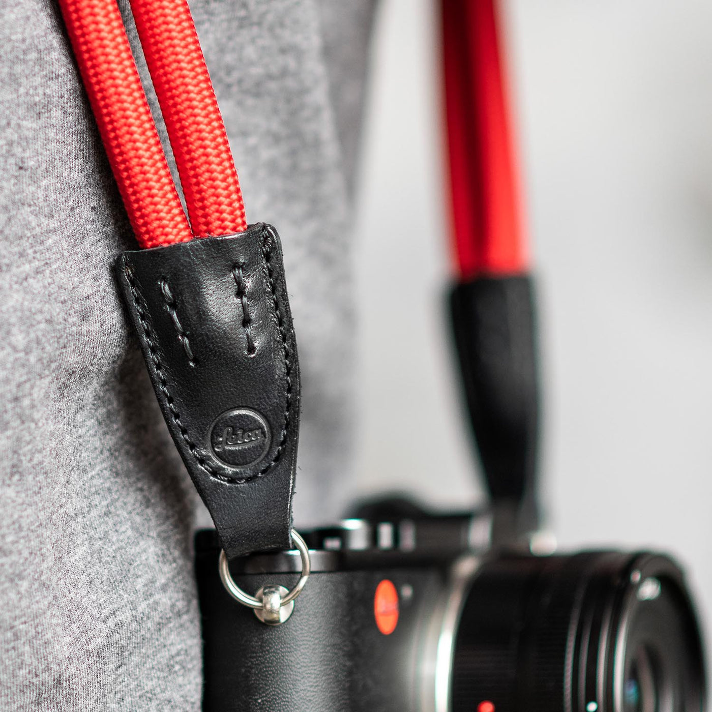 Leica camera on a photographer's hip held with red double rope strap 
