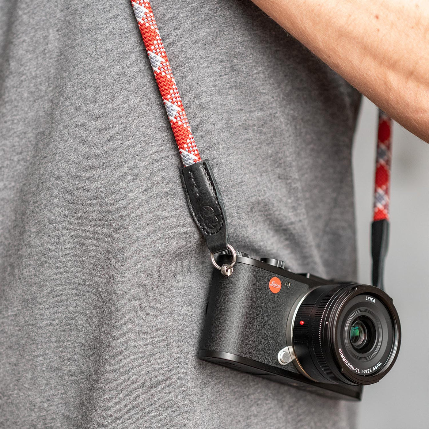 Leica camera on a photographer's hip held with red rope strap 