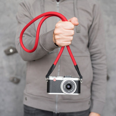 Photographer holding a leica camera by the strap 