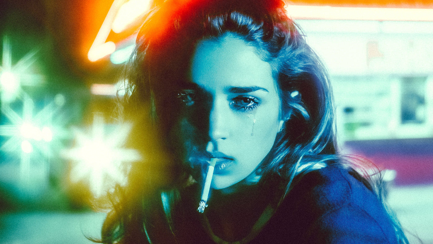 Portrait of a woman, smoking a cigarette, lit in colorful neon lighting and a shallow depth of field