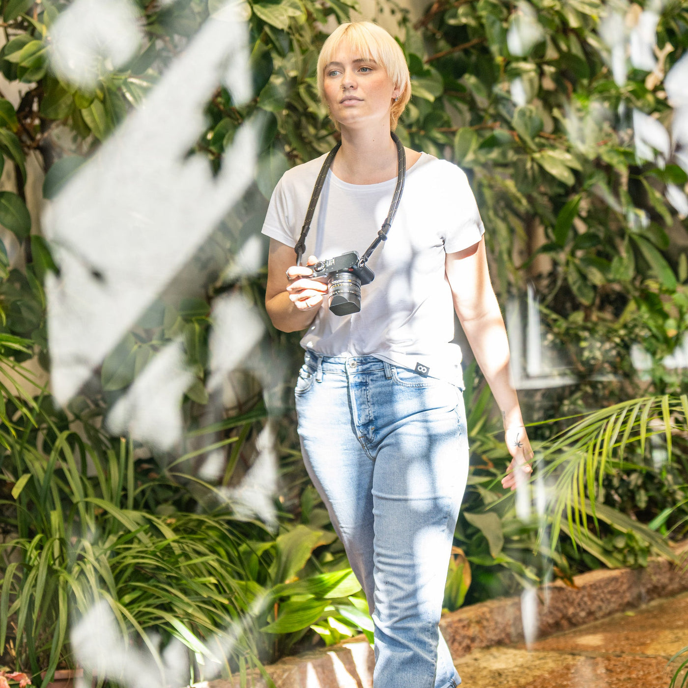 Female photographer walking in a greenhouse Leica Camera with Adjustable Rope Strap around her neck 