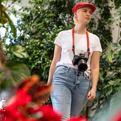 Female photographer walking in a greenhouse Sony Camera with Adjustable Rope Strap around her neck 