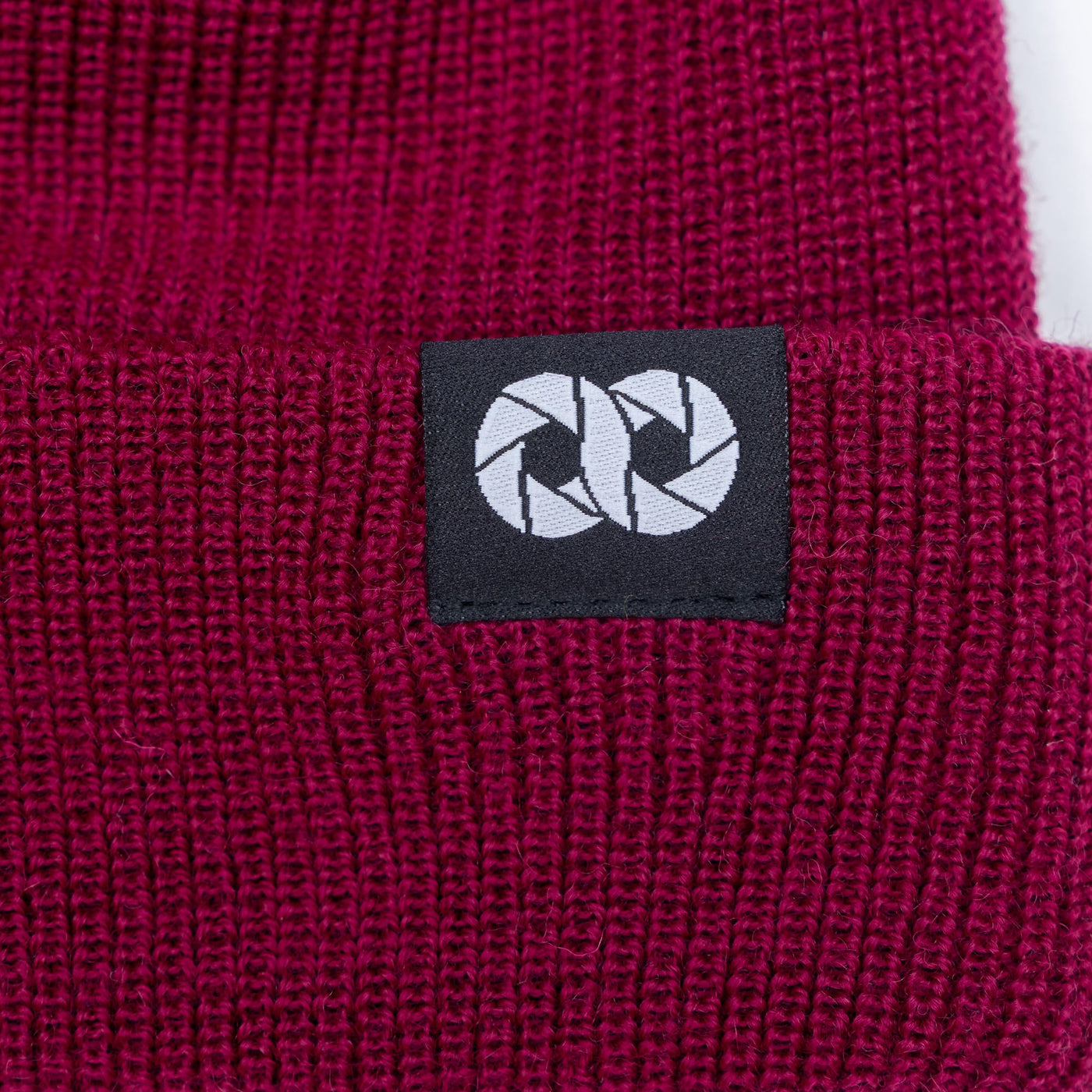 Close-up of a berry edc beanie with tag featuring cooph icon on a black background. --big 