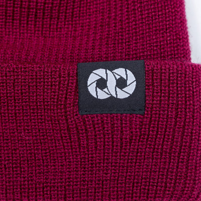Close-up of a berry edc beanie with tag featuring cooph icon on a black background. --big 