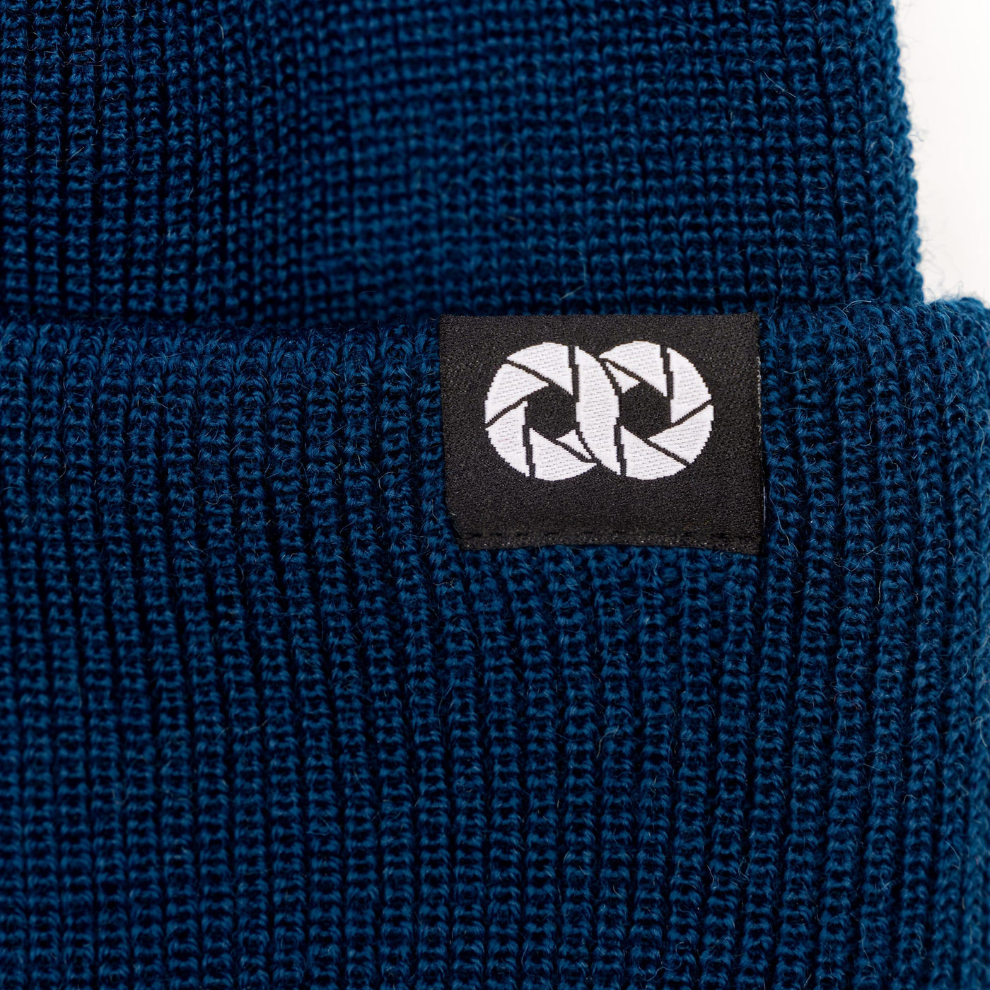 Close-up of a blue knit beanie with cooph logo tag on a white background ---big 