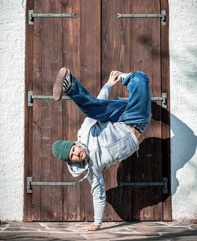 Break dancer doing a handstand against a wooden door and a white wall background