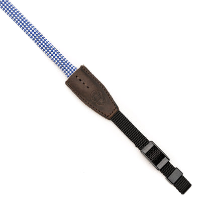 Blue and white checkered rope camera strap with brown leather steel ring endings on white background  