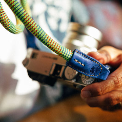 Close up of a photographer with Beers and cameras rope strap attached to a contax g2 \big 