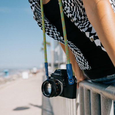 Photographer at the beach using Canon camera with Beers and camera rope strap 