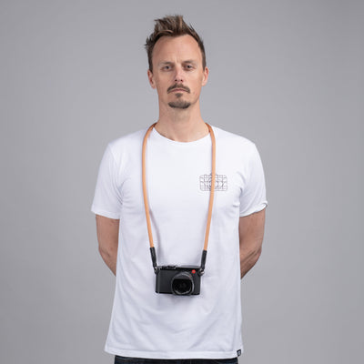 Photographer in a white t-shirt wearing a Leica camera around his neck with a Peach rope strap 