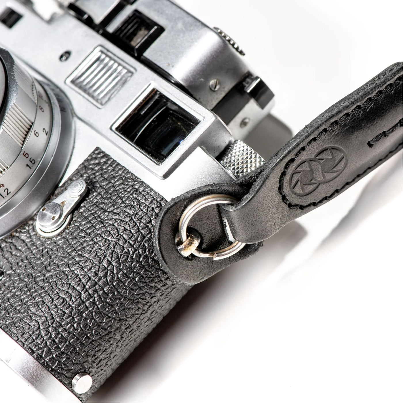 Close-up of a silver camera with leather strap on a white background 
