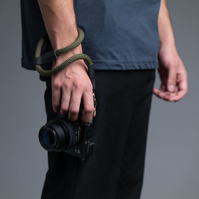 Photographer holding a camera attached to the wrist by the Rope Hand Strap 