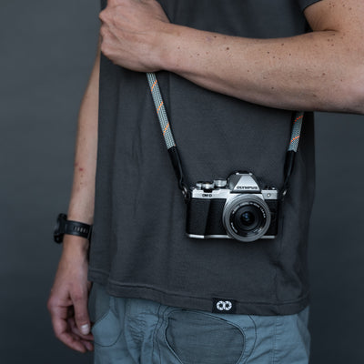 Olympus camera on a photographer's hip held with gray rope 