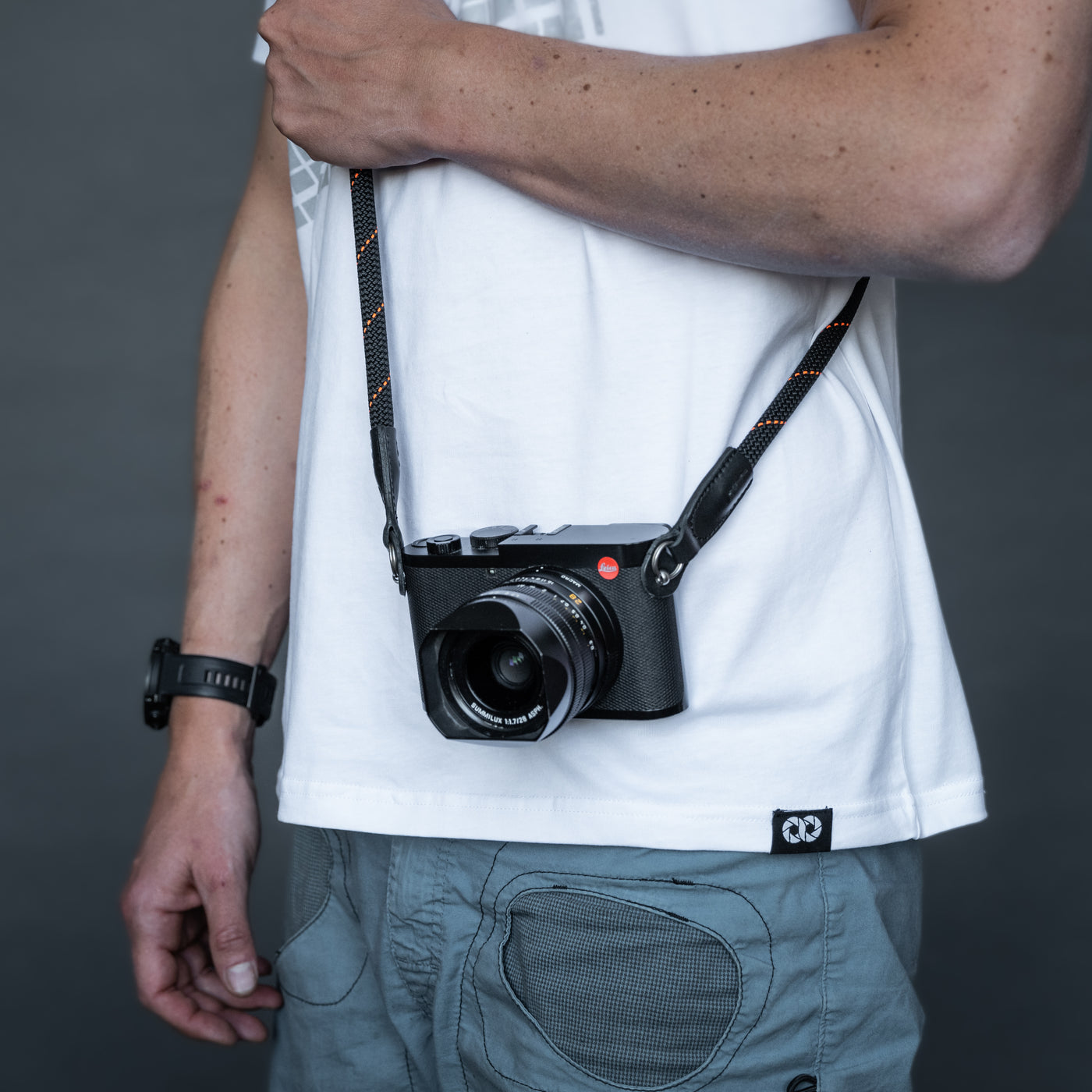 Leica camera on a photographer's hip held with black rope strap 