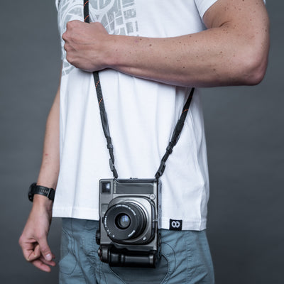 Retro camera on a photographer's hip held with black rope strap 
