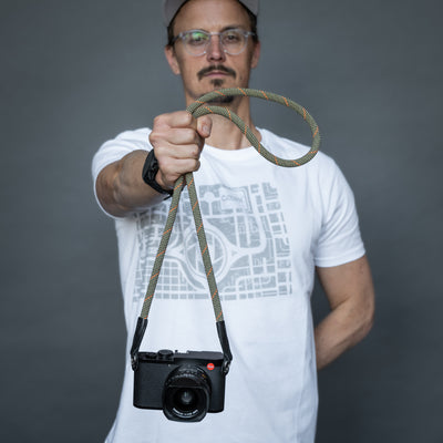 Photographer holding a camera attached to the wrist by the Rope Strap 