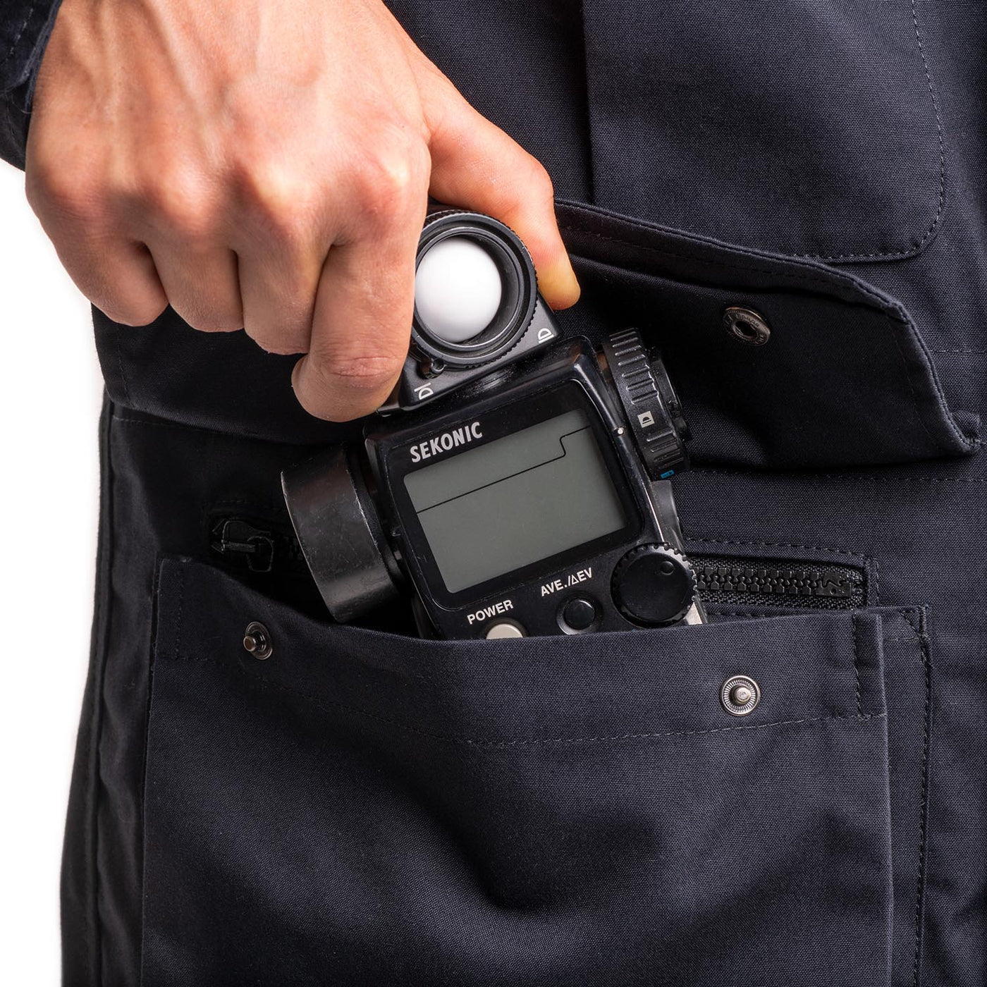 Photographer using one of the pockets on the field jacket to store a light sensor 