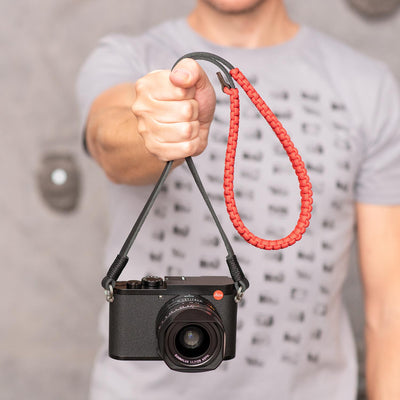 Photographer holding a camera by the paracord strap 