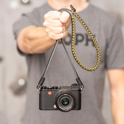 Photographer holding a camera by the paracord strap 