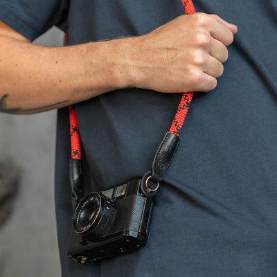 Retro camera on a photographer's hip held with red rope strap 