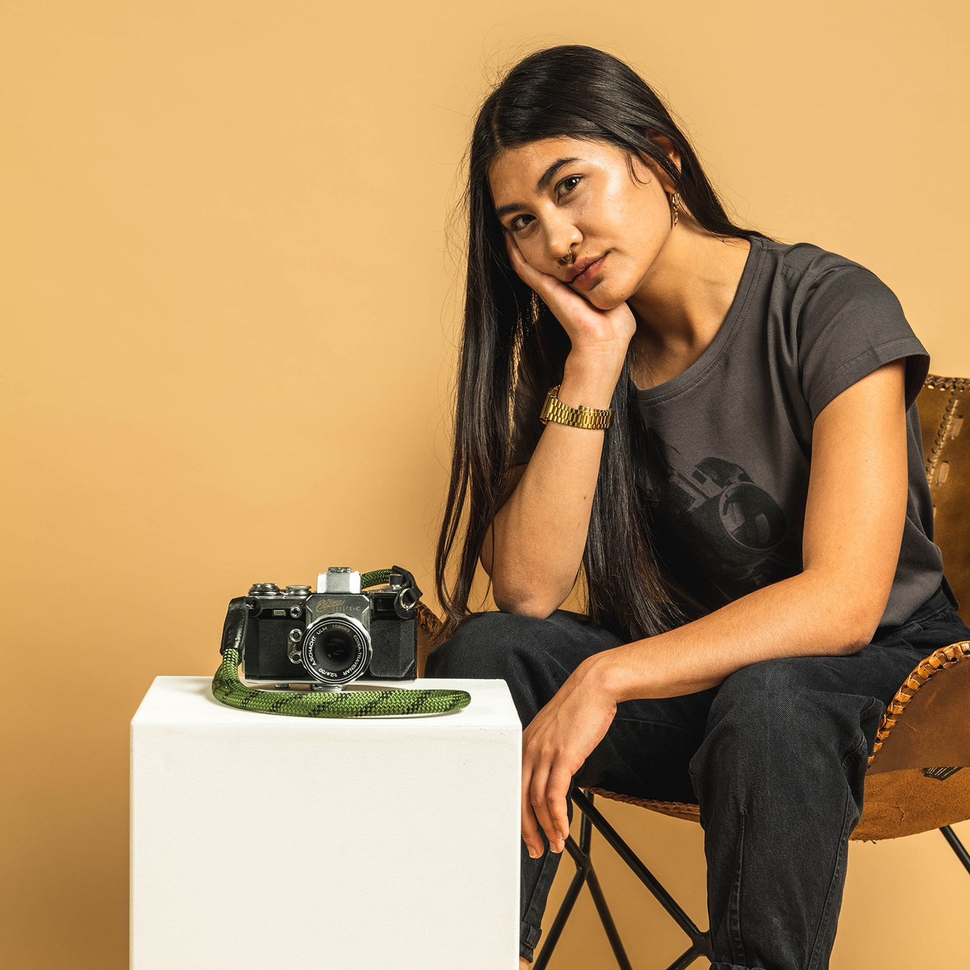 Photographer sat in a chair next to pedestal with a retro camera and rope strap 