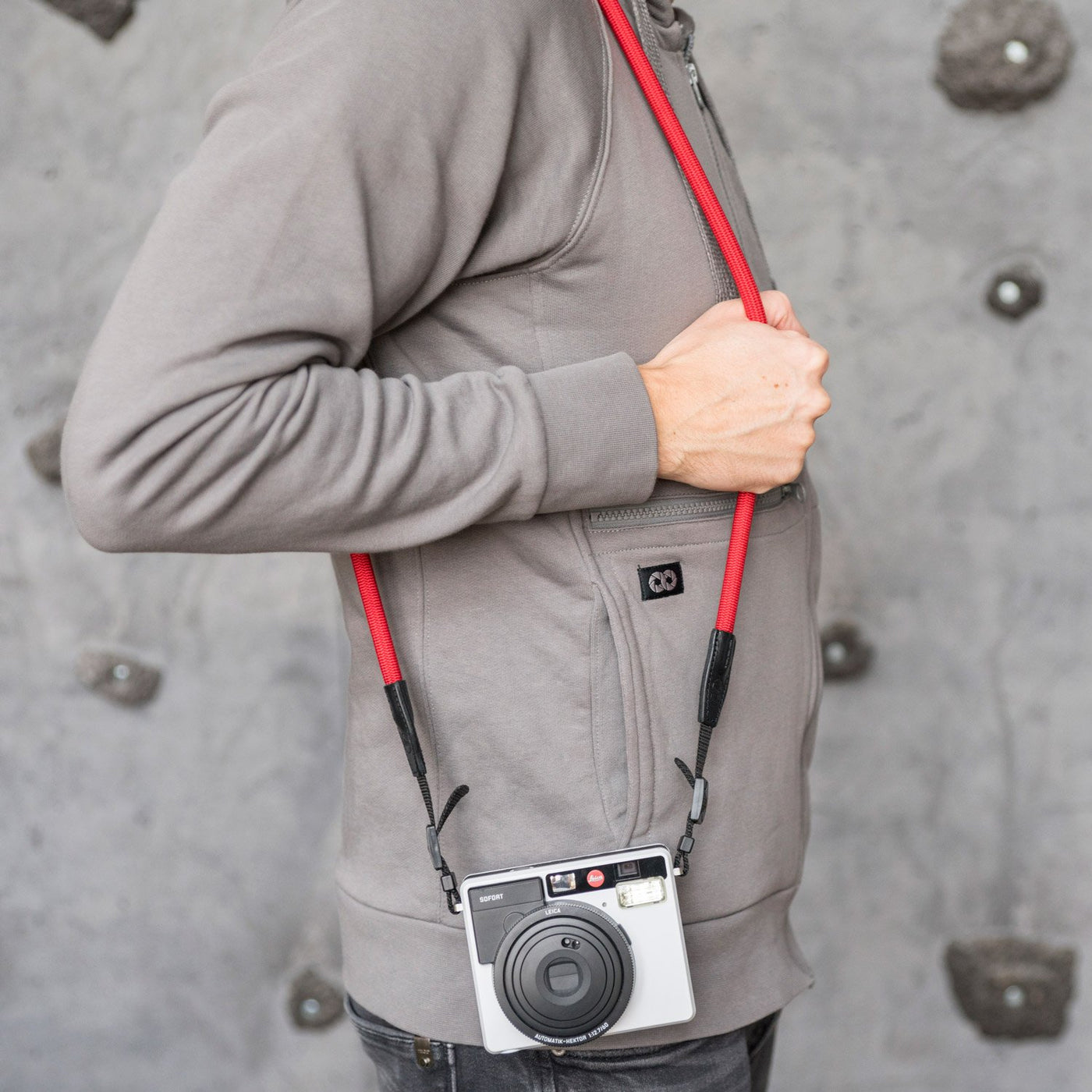 Leica camera on a photographer's hip held with red rope strap 