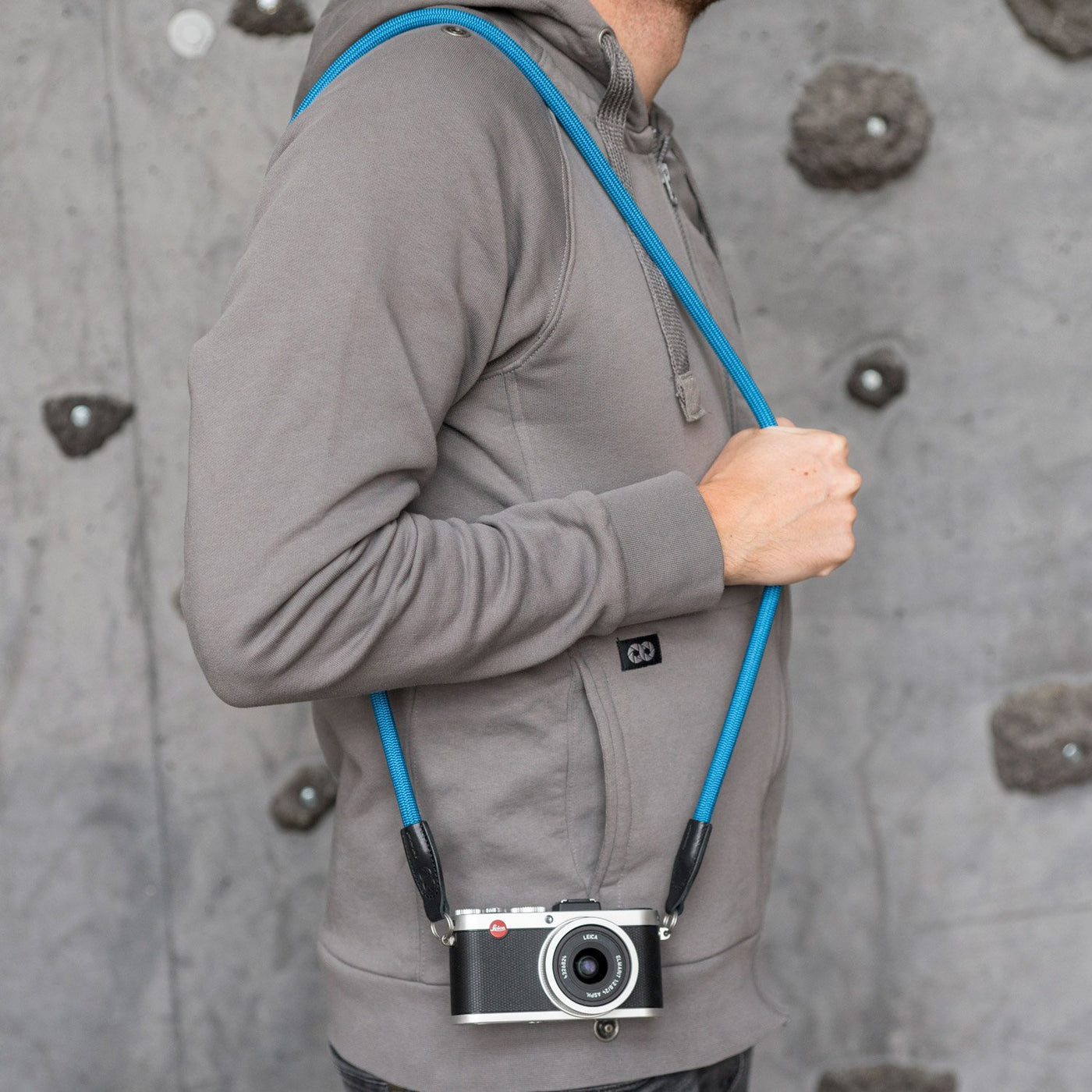 Leica camera on a photographer's hip held with blue rope strap 