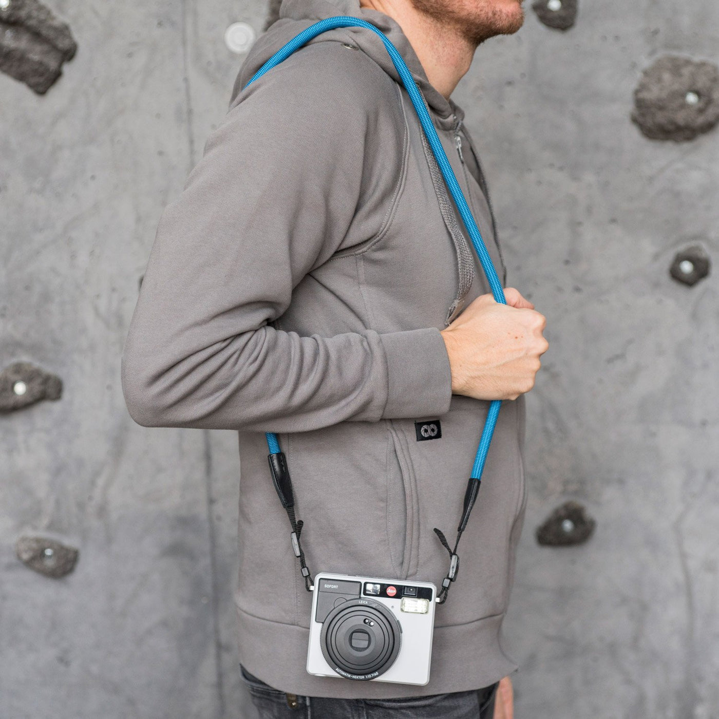 Leica camera on a photographer's hip held with blue rope 